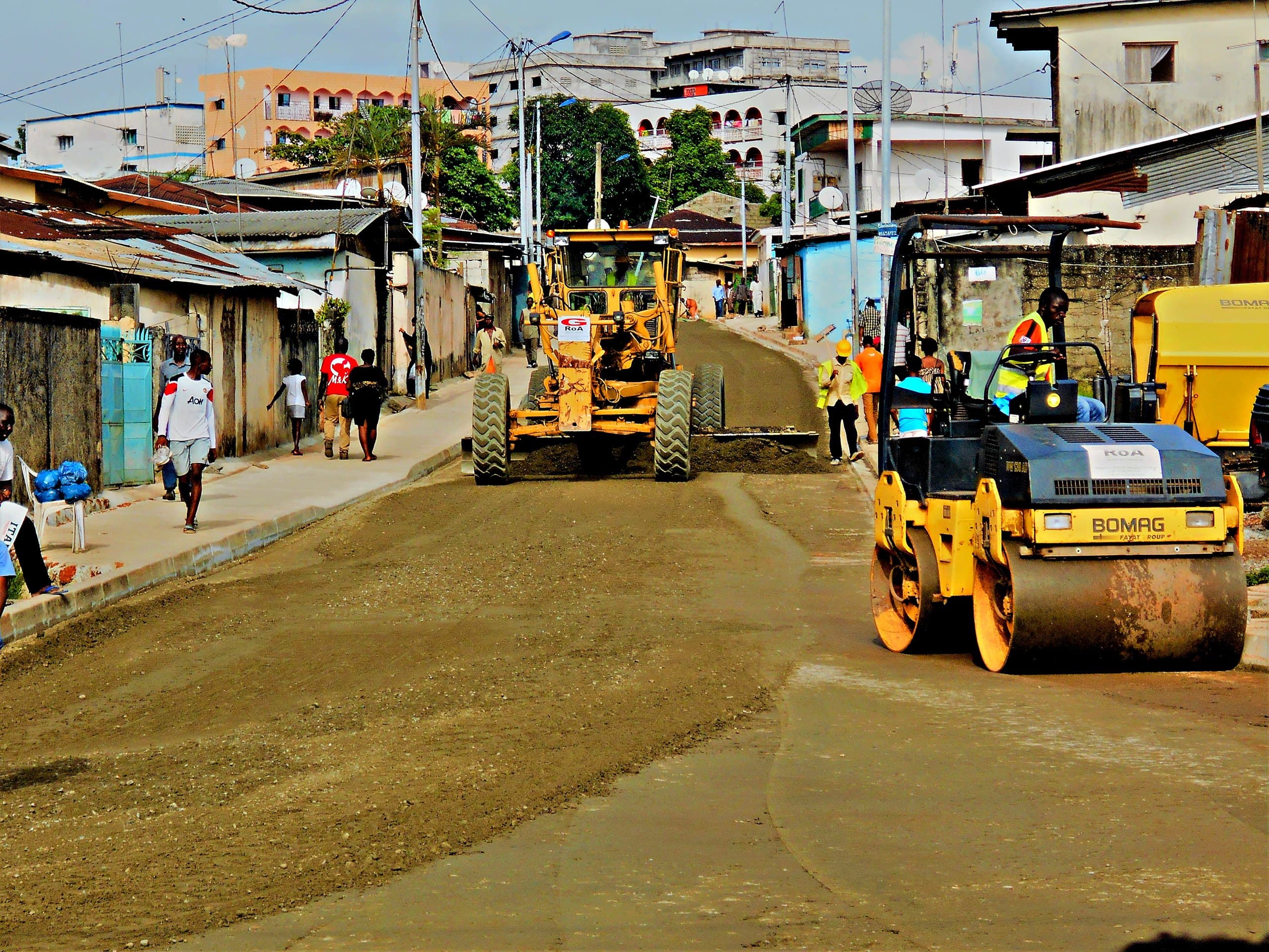 Niveleuse et compacteur GROA reprofilant une voirie de Libreville